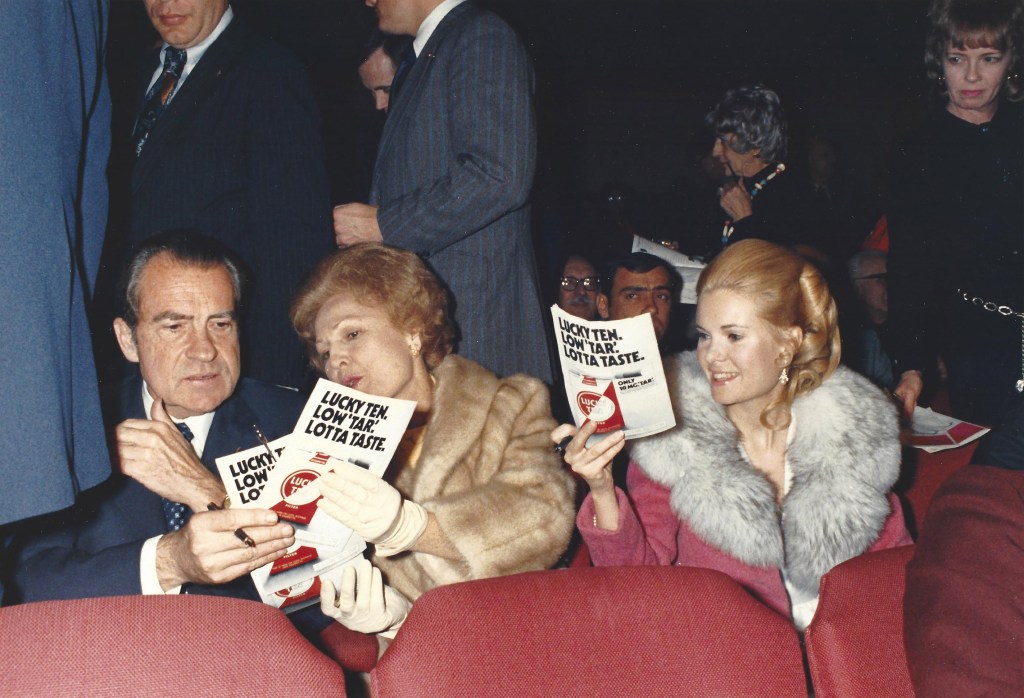 President Richard Nixon looks at a program alongside his wife, Pat, while seated at The National Theatre.